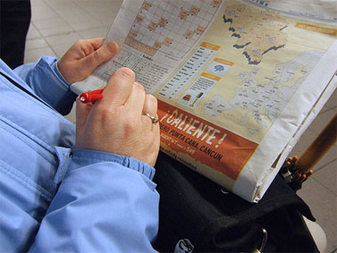 אדם פותר תשבץ בעיתון "מטרו" בתחנת רכבת בבריסל (צילום: Squonk, רישיון cc)