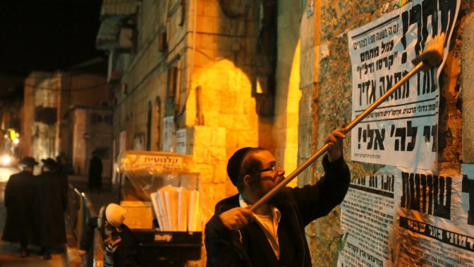 חרדי מדביק פשקווילים על קירות מאה-שערים בירושלים (צילום: נתי שוחט)