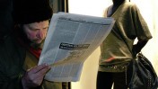 אדם קורא עיתון ליד חלון ראווה במולדובה (צילום: דורין ניקולסקו-מוסטטה, רשיון cc-by-nc-nd)