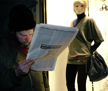 אדם קורא עיתון ליד חלון ראווה במולדובה (צילום: דורין ניקולסקו-מוסטטה, רשיון cc-by-nc-nd)