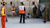 עובד הסהר-האדום עומד בין ליצנים פלסטינים לחיילים ישראלים, אתמול בחברון (צילום: מתניה טאוסיג)