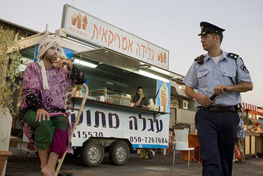 שוטר מביט במופע רחוב בירושלים (צילום: מתניה טאוסיג / פלאש 90)