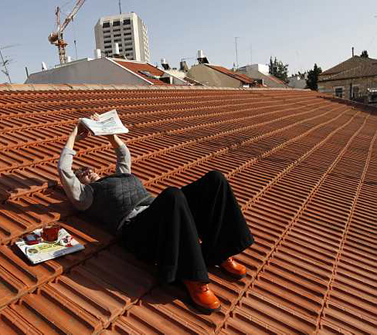 אשה קוראת עיתון על גג בית בשכונת נחלאות, אתמול בירושלים (צילום: נתי שוחט)