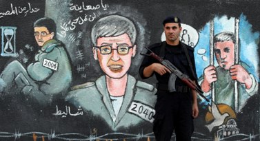 שוטר חמאס על רקע ציורי קיר של גלעד שליט (צילום: ויסאם נסאר)