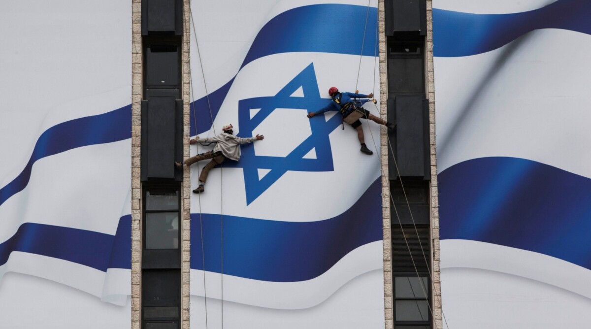 עובדים תולים דגל ישראל בכניסה לירושלים (צילום: יונתן זינדל)