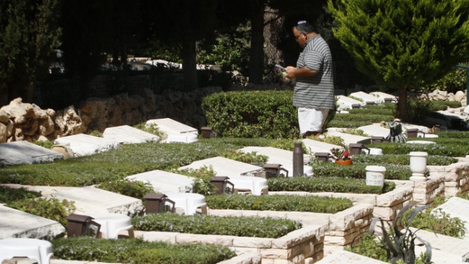 אדם ניצב לצד קברו של חייל שנהרג במלחמת יום-כיפור. בית העלמין הצבאי בהר-הרצל (צילום: אורי לנץ)