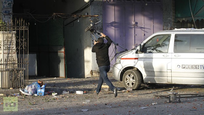 עיתונאים נסים מהבניין בו שכנו אולפי תחנת "אל-אקצא" של חמאס לאחר שהופצץ בידי צה"ל, 18.11.13 (צילום מסך: RT)