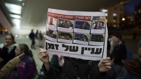 מפגינה נגד שחרור מחבלים מניפה תדפיס מתוך "ידיעות אחרונות". ירושלים, 29.12.13 (צילום: יונתן זינדל)