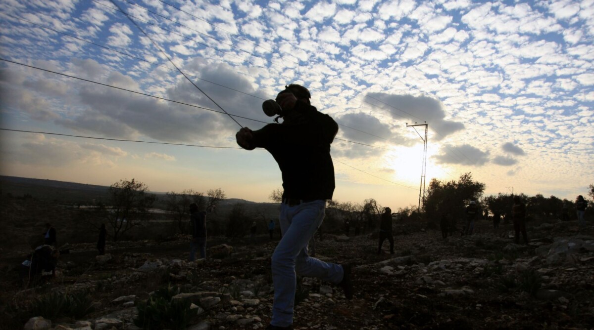 פלסטיני מיידה אבן לאחר לווייתו של סעיד ג'אסר עלי, בן 85, שלטענת עדי ראייה מת כתוצאה משאיפת גז מדמיע. 2.1.14 (צילום: עיסאם רימאווי)