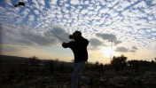 פלסטיני מיידה אבן לאחר לווייתו של סעיד ג'אסר עלי, בן 85, שלטענת עדי ראייה מת כתוצאה משאיפת גז מדמיע. 2.1.14 (צילום: עיסאם רימאווי)