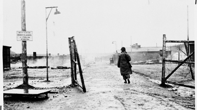חייל אמריקאי צועד דרך שער מחנה העבודה קאופרינג 1 (לנדסברג) המסונף למחנה הריכוז דכאו ביום שחרור המחנה, 27.4.1945 (צילום: National Archives and Records Administration, College Park, נחלת הכלל)