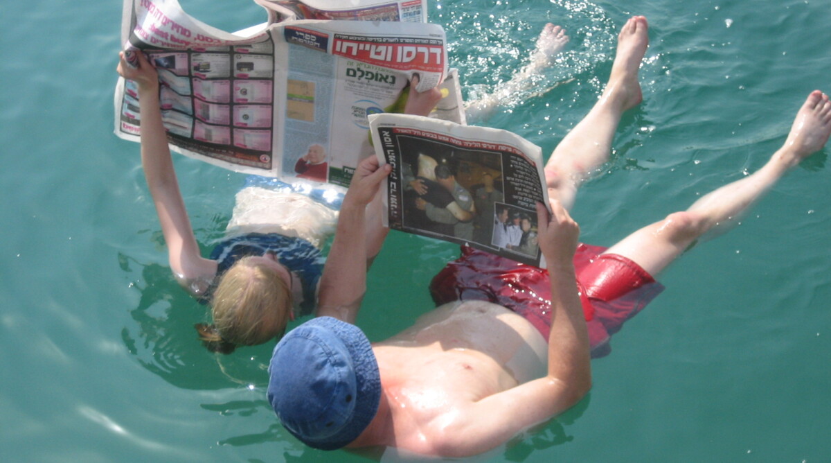 אנשים קוראים עיתון בים המלח. (צילום: Dana&Ron, רישיון cc-by-nc-sa)