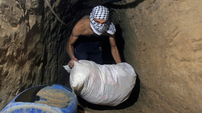 פלסטיני רעול פנים מעביר שק במנהרה, היום לפני שש שנים. רצועת עזה, 29.7.08 (צילום: פאדי עדואן)