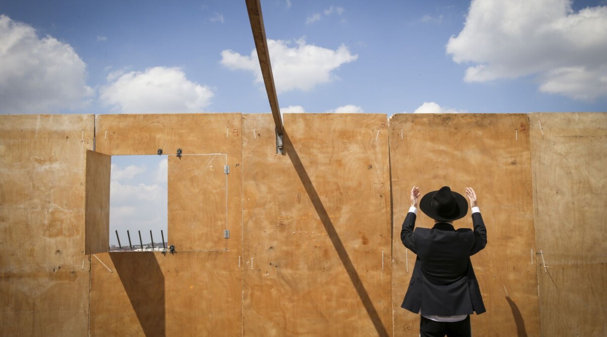 גבר חרדי מתפלל מול קיר של סוכה בבנייה. ביתר-עילית, 3.10.14 (צילום: נתי שוחט)