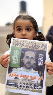 בת משפחתו של המחבל מחזיקה כרזה לזכרו, 5.11.14 (צילום: סלימאן ח'אדר)