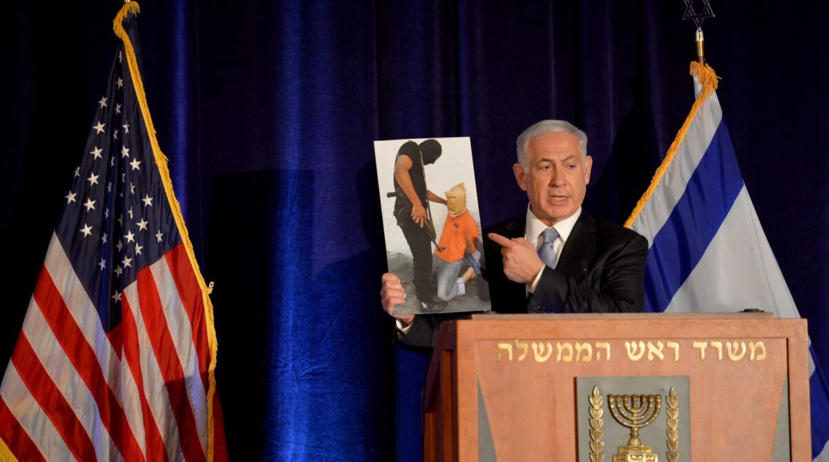ראש ממשלת ישראל, בנימין נתניהו, מציג תצלום שבו נראה פלסטיני חמוש מרצועת עזה בסצנה המזכירה את ההוצאות להורג של ארגון דאע"ש (צילום: אבי אוחיון, לע"מ)