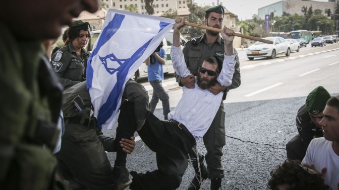 שוטר מג"ב מרים מפגין באירוע מחאה נגד פיגועים. ירושלים, 2.10.15 (צילום: הדס פרוש)