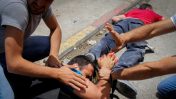 צלם פלסטיני פצוע שוכב ליד גופת פלסטיני שנורה על ידי ישראלי שרכבו נרגם באבנים, חווארה, 18.5.17 (צילום: נאסר אישתייה)