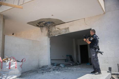 שוטר ישראלי מצלם נזק שגרמה רקטה עזתית בשדרות, 9.8.2018 (צילום: יונתן זינדל)