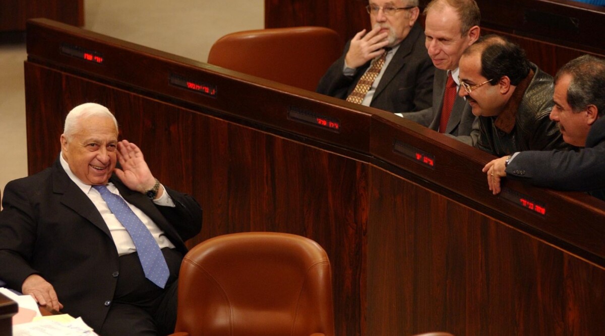 אריאל שרון וח"כים חולקים רגע מחויך במליאת הכנסת, 2004 (צילום: פלאש 90)