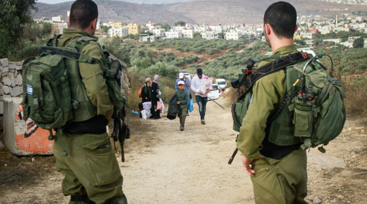 חיילים ישראלים משקיפים על פלסטינים בצאתם למסיק זיתים ליד הכפר סאלם שבגדה המערבית. 15.10.2019 (צילום: נאסר אישתיה)