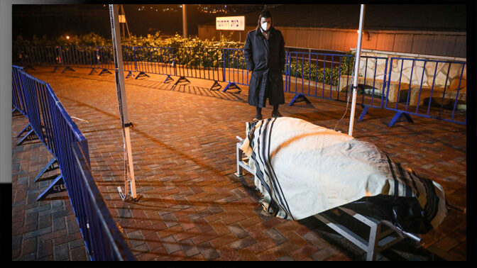 אדם עומד ליד גופתו של אריה אבן, האדם הראשון בישראל שנפטר כתוצאה מנגיף הקורונה; הר המנוחות, ירושלים, 22.3.2020 (צילום: יונתן זינדל)