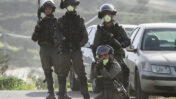 שוטרים לובשים מסכות נגד קורונה במהלך התנגשויות עם מפגינים פלסטינים בג'בל אל ערמה, ב-11 במרץ 2020 (צילום: נאסר אישתאיה)