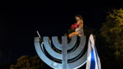 מפגינה יושבת על פסל מנורה ליד הכנסת ומתפשטת, 21.7.20 (צילום: יונתן זינדל)