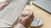 אדם קורא עיתון ושותה קפה