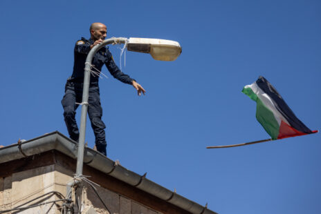 שוטר מתיר דגל פלסטיני שנקשר לעמוד על-ידי מפגינים חרדים, מאה שערים, ירושלים, 8.7.24 (צילום: חיים גולדברג)