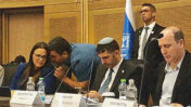 אלעד זמיר, ראש המטה של שר התקשורת שלמה קרעי, לוחש על אוזנה של יו"ר "ועדת התקשורת" ח"כ גלית דיסטל-אטבריאן. מימין: מנכ"ל משרד התקשורת אלעד מקדסי ושר התקשורת שלמה קרעי; ישיבת ועדת התקשורת, 8.12.25 (צילום מתוך שידורי הוועדה)