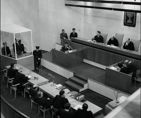 משפט אייכמן (משמאל בתא הזכוכית), עם השופטים (מימין לשמאל) יצחק רווה, משה לנדוי ובנימין הלוי, בית העם בירושלים, 15.12.1961 (צילום: לע"מ)